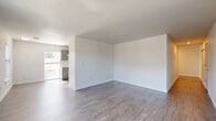 Located at 233 N Main St in Brighton, Colorado, this single-floor, 3-bedroom, 2-bathroom home presents a clean and contemporary aesthetic throughout. Wood-look luxury vinyl flooring runs consistently across all rooms, complementing the bright white walls and crisp white baseboards that give the space a fresh, well-maintained feel.

The open living room features a large picture window that fills the room with natural light and offers views of the surrounding neighborhood. The kitchen is efficiently laid out with gray shaker-style cabinetry, white countertops, a full suite of white appliances including an electric range and dishwasher, and a range hood overhead. Windows in the kitchen allow additional natural light to brighten the workspace.

The three bedrooms are each well-proportioned and bright, with windows that bring in ample daylight. The generously sized primary bedroom provides comfortable living space, while the two additional bedrooms are versatile for use as guest rooms, home offices, or more. Two closets offer practical storage solutions throughout the home.

The two bathrooms are tastefully appointed — one features a tub-shower combination with a gray vanity and large mirror, while the second offers a walk-in shower stall with built-in shelving, a dark vanity, and mirrored medicine cabinet. Both bathrooms maintain the consistent modern palette found throughout the home.