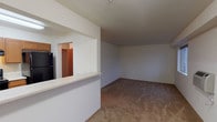 Located at 4034 Idlewild Loop in Coeur d'Alene, Idaho, this single-floor unit offers a practical and well-organized layout suited for comfortable everyday living. The kitchen is outfitted with warm honey-toned wood cabinetry, light countertops, hardwood-style flooring, a black refrigerator, dishwasher, and stove, providing ample prep and storage space. A pass-through counter opens the kitchen toward the living area, creating a connected and sociable flow between spaces. Conveniently accessible from the kitchen is a dedicated laundry room equipped with a full-size washer and dryer, along with additional shelving for storage. The spacious living room features neutral carpet and clean white walls, offering a blank canvas for personalization. The bedrooms are generously sized with plush carpeting, large windows that invite natural light and outdoor views of the surrounding neighborhood and treeline, and walk-in closets providing excellent storage. The bathroom is finished with a wood-toned vanity, light countertop, hardwood-style flooring, and a shower-tub combination. Throughout the unit, a consistent palette of neutral tones and warm wood accents creates a cohesive and inviting atmosphere.