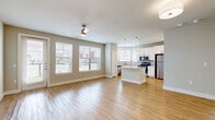 This thoughtfully designed single-floor residence offers a comfortable and efficient layout across one bedroom and two bathrooms. Light wood-look flooring flows consistently throughout the entire space, lending warmth and visual continuity to every room.

The open-concept living and kitchen area forms the heart of the home. The living room is generously proportioned, featuring a ceiling fan, neutral taupe walls, and multiple large windows dressed with white blinds that invite an abundance of natural light. A sliding glass door provides additional brightness and outdoor access.

The kitchen is well-appointed with white shaker-style cabinetry, granite countertops, stainless steel appliances including a refrigerator, range, and microwave, and a central island that adds both prep space and a visual anchor to the open layout. Pendant lighting above the island adds a polished finishing touch.

The spacious primary bedroom includes a ceiling fan, a window with outdoor views, and direct access to a well-sized walk-in closet outfitted with wire shelving systems for organized storage. The primary bathroom impresses with a double-sink vanity topped with granite counters, a soaking tub, and floor-to-ceiling marble-style tile surrounding the tub and shower. A second full bathroom serves additional needs. Clean, neutral tones throughout create a bright and cohesive ambiance.