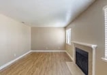 Located at 505 Pioneer in Lodi, CA, this single-story 2-bedroom, 2-bathroom unit offers a well-organized and functional layout. The living room serves as the heart of the home, featuring a tile-surround fireplace, wood-look laminate flooring, and a window fitted with blinds that allows natural light to filter in. The entry door opens directly into this welcoming space, lending an open and accessible feel. The kitchen is efficiently designed in a U-shaped configuration, showcasing white cabinetry with ample upper and lower storage, granite-style countertops, a gas range, and a full-size refrigerator, all complemented by matching wood-look flooring. Both bedrooms are carpeted for comfort and painted in warm neutral tones. The primary bedroom includes a mirrored sliding-door closet with built-in shelving, providing excellent storage. The second bedroom features a window with blinds, offering natural light. Each bathroom is equipped with a full-size soaking tub and shower combination with clean white surrounds and chrome fixtures. A textured ceiling runs throughout the unit. Outside, covered carport parking is available amid a landscaped setting with mature trees, providing shade and a pleasant exterior environment.
