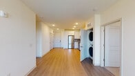 This single-floor residence at 11210 Peppermint St in Louisville, Kentucky presents a clean, contemporary design with an emphasis on functional living. The open-concept main area connects the living space to the kitchen, both finished with warm-toned hardwood-style flooring that runs consistently throughout the common areas. Recessed lighting illuminates the space efficiently, complementing the neutral white walls and creating a bright, welcoming atmosphere.

The kitchen is well-appointed with crisp white shaker-style cabinetry extending to the ceiling for generous storage, light quartz countertops, a gray tile backsplash, and a full suite of stainless steel appliances including a refrigerator, electric range, over-the-range microwave, and dishwasher. A dedicated closet near the main living area houses a stacked washer and dryer for in-unit laundry convenience.

The bedrooms feature plush carpeting and ceiling fans, with windows that bring in natural light. One bathroom includes a white vanity with quartz countertop, a framed mirror, tile flooring, and a tiled walk-in shower, while a second bathroom offers a tub-shower combination with coordinating tile surround. A spacious walk-in closet with wire shelving provides ample storage.