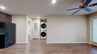 Located in Conway, Arkansas, this single-story home offers a well-designed layout with a practical mix of finishes and functional living spaces throughout. The kitchen is a standout feature, equipped with rich dark wood cabinetry, granite-look countertops, and black appliances including an electric range, built-in microwave, dishwasher, and refrigerator. Wood-look luxury vinyl flooring runs through the kitchen and main living areas, adding warmth and durability. The living area is bright and open, highlighted by a ceiling fan and French doors that invite natural light and provide access to the outdoors. The bedrooms are carpeted for comfort and each features a ceiling fan and windows with blinds for light control. The primary bedroom includes convenient access to the stacked washer and dryer unit, keeping laundry centrally located. The bathroom is clean and straightforward, featuring a tub-shower combo, a toilet, and a vanity with granite-look countertop and dark wood cabinetry. Neutral wall tones and recessed lighting are consistent throughout, creating a cohesive and inviting atmosphere across the entire home.