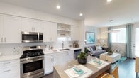 Located at 1660 Metro in Chula Vista, this model unit offers a well-appointed single-floor layout designed with modern living in mind. The open-concept kitchen serves as the heart of the home, featuring crisp white shaker cabinetry, open shelving, a classic subway tile backsplash, sleek quartz countertops, and a full suite of stainless steel appliances including a gas range, microwave, dishwasher, and refrigerator. A central island with bar seating provides an ideal space for casual dining and entertaining, while dark hardwood-style flooring anchors the space with warmth and sophistication. The kitchen flows seamlessly into the living area, creating a bright and cohesive open layout. The bedroom is a serene retreat, accented by a bold teal patterned feature wall, plush carpeting, and windows dressed with layered curtains that allow for natural light while maintaining privacy. A ceiling fan adds comfort, and a mirrored sliding-door closet provides practical storage. The bathroom is clean and functional, finished in white tile with a full tub-shower combination and dark hardwood-style flooring that ties back to the main living areas. Throughout the unit, a coastal-inspired color palette of teal, white, and grey lends a fresh and inviting ambiance.