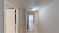 This two-floor residential space offers a well-organized layout designed for comfortable everyday living. The interior is finished with light neutral tones throughout, accented by white crown molding and textured ceilings that add a classic touch to each room.

The main level features light ceramic tile flooring that runs through the entry hallway, living areas, and kitchen. The hallway leads into an open living space with access to a sliding glass door dressed with vertical blinds, allowing natural light to fill the room. A ceiling fan overhead adds both function and style. Adjacent to the living area, the kitchen is equipped with gray cabinetry, a double stainless steel sink, granite-style laminate countertops, a white subway tile backsplash, and black appliances including a refrigerator and dishwasher.

The lower level also includes a full bathroom with a tub-shower combination, tile flooring, a vanity with granite-style countertop, and crown molding details.

Upstairs, the second floor offers carpeted bedrooms with ceiling fans, closet space, and windows with natural light. A second bathroom on this level includes tile flooring, a single vanity with granite-style countertop, and a well-lit mirror. The combination of practical finishes and multi-level design makes this a functional and inviting residential space.