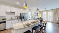 Located at 60 Caliza Circle in St. Augustine, Florida, this single-story residence offers a thoughtfully designed open-concept layout with a cohesive, modern aesthetic. The kitchen serves as a central hub of the home, showcasing white shaker cabinetry, white subway tile backsplash, granite countertops, and a full suite of stainless steel appliances. A curved kitchen island with seating extends into the dining and living areas, creating a seamless flow ideal for both everyday living and entertaining. Statement metallic pendant lights add a stylish focal point overhead, while wood-look flooring grounds the main living spaces.

The bedrooms are carpeted for comfort and feature ceiling fans, generous natural light from large windows framing lush outdoor views, and neutral tones that lend a calm, airy feel. The primary suite includes a spacious walk-in closet with built-in wire shelving and an en-suite bathroom equipped with a dual-sink vanity, granite countertops, a glass-enclosed shower, and wood-look flooring. A secondary bathroom mirrors the same clean, white finishes and connects conveniently to an additional bedroom. Throughout the home, bright walls and consistent finishes create a polished, welcoming atmosphere.