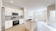 This thoughtfully laid-out one-bedroom, two-bathroom residence offers a bright and modern living experience with a clean, contemporary aesthetic throughout. The open-concept kitchen and living area forms the heart of the home, where the kitchen stands out with crisp white shaker cabinetry extending to the ceiling, granite countertops, a suite of stainless steel appliances including a side-by-side refrigerator with ice maker, electric range, and built-in microwave, and a central island with an undermount sink — ideal for both cooking and casual dining. Light hardwood-style flooring flows seamlessly across all living areas, enhancing the sense of openness and continuity. The living room benefits from natural light through a window overlooking greenery, complemented by a ceiling fan. The bedroom is a comfortable, sun-filled retreat featuring its own ceiling fan, a window with outdoor views, and direct access to a spacious walk-in closet outfitted with multi-tier wire shelving for ample storage. The bathrooms are finished with elegant marble-style tile in the tub/shower surround, offering a polished, upscale feel. Neutral wall tones and clean lines throughout create a calm, move-in-ready environment.