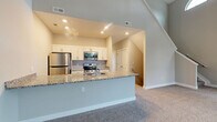 Located at 7353 Woodall Rd in Aurora, Ohio, this well-appointed two-story home offers 3 bedrooms, 3 bathrooms, and a versatile loft spread across two thoughtfully designed floors. The main level hosts an open-concept kitchen and living area, where the kitchen stands out with crisp white shaker cabinetry, granite countertops, stainless steel appliances, a undermount sink, and light hardwood-style flooring. The living area features impressively soaring ceilings with an arched transom window that floods the space with natural light, complemented by plush carpet and a staircase leading to the upper level. Upstairs, the loft provides a flexible open space bathed in natural light from a charming arched window, ideal for a home office or lounge. The spacious primary bedroom includes sliding glass doors opening to a private balcony with neighborhood views, plush carpeting, and an en suite bathroom featuring granite countertops, white cabinetry, and wood-look flooring with access to a walk-in closet with built-in shelving. Additional bedrooms are well-sized with carpet flooring and ample closet storage. The home also includes a dedicated laundry area, a utility room, and four closets throughout, offering abundant storage and functional everyday living.