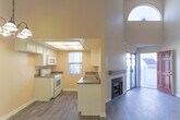 This two-story residence in Riverside, California offers a well-designed layout spread across two levels. The main floor features a spacious living area with soaring vaulted ceilings, a wood-mantled fireplace, and durable wood-look plank flooring that extends throughout the lower level. The kitchen is equipped with white cabinetry, dark granite-style countertops, a double stainless steel sink, a gas range, dishwasher, and a skylight that fills the space with natural light. A window with vertical blinds provides additional brightness and ventilation. A full bathroom on the lower level features a single-sink vanity, a tub-shower combination, and wood-look flooring. Upstairs, the loft-style second floor is defined by exposed ceiling beams, plush carpeting, and an arched window that brings in natural light. The upper level also includes additional rooms with angled ceilings, carpet flooring, and generous closet space. Throughout the home, neutral warm tones create a cohesive and welcoming atmosphere. A staircase with a landing connects both floors, contributing to the home's open and airy feel.