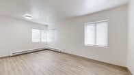 Located at 2174 NW Davis St in Portland's Northwest District, this single-floor unit offers a clean, functional layout spread across seven distinct spaces. Light wood-style flooring runs consistently throughout, lending warmth and visual continuity to the entire floor plan. The living area is generously proportioned and bathed in natural light from a corner bay window arrangement paired with an additional side window, creating an airy, open atmosphere. Baseboard heaters are present throughout, ensuring reliable warmth year-round. The kitchen features distinctive blue cabinetry with granite-style countertops wrapping in an L-shape, complemented by a white electric range, vent hood, and a window that allows natural light into the cooking space. The bedroom includes a dedicated closet with a built-in shelf rod, offering practical storage. Additional rooms include smaller, versatile spaces well-suited for a home office, storage, or den use. Crisp white walls throughout contribute to a bright, neutral aesthetic. The layout, as visible in the floorplan overview, is compact yet efficiently organized, making excellent use of the available square footage. This unit combines everyday practicality with a clean, modern finish in a well-connected Portland neighborhood.