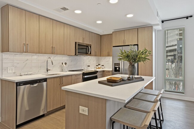 Gourmet Kitchen And Dining Area With White Countertops, Rustic Taupe Cabinets, and Stainless-Steel Appliances - High Street Atlanta