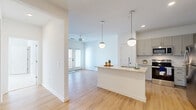 Located at 510 Cedar Tree Rd in Wellford, South Carolina, this well-appointed one-bedroom, one-bathroom residence offers a thoughtfully designed open-concept layout. Light-toned hardwood flooring flows throughout the main living areas, enhancing the bright, airy atmosphere created by white walls and abundant natural light.

The kitchen is a standout feature, showcasing gray shaker-style cabinetry, a classic subway tile backsplash, and a full suite of stainless steel appliances including a refrigerator, range, microwave, and dishwasher. A central island with a granite countertop and undermount sink serves as both a prep space and casual dining area, illuminated by a pair of modern globe pendant lights overhead.

The open living and dining area extends seamlessly from the kitchen, featuring a ceiling fan and French doors that open to a private balcony with outdoor views. The spacious bedroom is finished with plush carpet, a ceiling fan, and a dedicated closet with a built-in hanging rod for organized storage. The full bathroom is equipped with a soaking tub and tiled shower surround. A hallway connects the rooms efficiently, completing this functional and stylish single-floor layout.