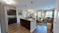 Located at 380 Mather St in Hamden, Connecticut, this single-floor residence offers a thoughtfully designed open-concept layout that seamlessly connects the kitchen, dining, and living areas. The kitchen is a standout feature, showcasing rich dark cabinetry, granite countertops, stainless steel appliances including a gas range and refrigerator, and a central island with bar seating illuminated by pendant lighting — ideal for both cooking and casual dining. Adjacent to the kitchen, a dedicated dining nook is distinguished by bold botanical wallpaper, a large grid-style mirror, and an elegant chandelier, creating an intimate yet stylish atmosphere. The living room offers a warm, inviting ambiance with soft sage-green walls, large windows that invite abundant natural light and outdoor views, and hardwood-style flooring that flows throughout the space. The bedroom is a serene retreat featuring calming neutral tones, multiple windows with views of the surrounding greenery, and access to a closet and en-suite bath. The bathroom is finished with a dual-sink dark wood vanity, framed mirrors, and neutral tile flooring. An in-unit laundry area adds everyday convenience to this well-appointed residence.