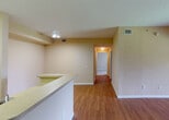 Located at 4495 Emerald Vista in Lake Worth, Florida, this single-floor residence offers a well-organized layout with a warm, neutral color palette throughout. The main living area features rich wood-look flooring and opens directly to the kitchen via a pass-through counter, creating a connected and functional common space. A decorative arched entryway with column accents adds architectural character to the living room, which also benefits from natural light filtering in through windows.

The kitchen is efficiently designed with white cabinetry, white appliances including an electric range and refrigerator, and light countertops. A louvered closet door adjacent to the kitchen provides convenient utility or pantry storage.

The bedrooms are carpeted for comfort and each features windows with views of the surrounding greenery, lending a serene, nature-connected atmosphere. The primary bedroom includes direct access to a private bathroom with a vanity, mirror, and an additional water closet, as well as a dedicated closet space.

The bathrooms are finished with light wood-look flooring, white cabinetry, tile-surround tub-shower combinations, and well-lit vanities. Textured walls and consistent neutral tones tie the interior together, creating a cohesive and practical living environment throughout the home.