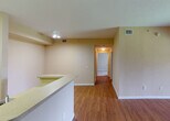 Located at 4495 Emerald Vista in Lake Worth, Florida, this single-floor residence offers a well-organized layout with a warm, neutral color palette throughout. The main living area features rich wood-look flooring and opens directly to the kitchen via a pass-through counter, creating a connected and functional common space. A decorative arched entryway with column accents adds architectural character to the living room, which also benefits from natural light filtering in through windows.

The kitchen is efficiently designed with white cabinetry, white appliances including an electric range and refrigerator, and light countertops. A louvered closet door adjacent to the kitchen provides convenient utility or pantry storage.

The bedrooms are carpeted for comfort and each features windows with views of the surrounding greenery, lending a serene, nature-connected atmosphere. The primary bedroom includes direct access to a private bathroom with a vanity, mirror, and an additional water closet, as well as a dedicated closet space.

The bathrooms are finished with light wood-look flooring, white cabinetry, tile-surround tub-shower combinations, and well-lit vanities. Textured walls and consistent neutral tones tie the interior together, creating a cohesive and practical living environment throughout the home.