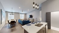 Located at 3012 N Hills Blvd in North Little Rock, AR, this thoughtfully designed 3-bedroom, 2-bathroom home offers a seamless open-concept layout across a single floor. The kitchen serves as a central focal point, featuring a generous curved island with seating, stainless steel appliances, white quartz countertops, glass-front cabinetry, and striking pendant lighting that soars toward the dramatically high ceilings. The kitchen flows naturally into both the dining area and the living room, creating an ideal space for entertaining. The dining area features vaulted ceilings, a modern chandelier, and abundant natural light from large windows. The living room is bright and welcoming, with recessed lighting, a ceiling fan, and multiple windows that invite natural light throughout. The spacious primary bedroom includes plush carpeting, a wall-mounted TV, and direct access to a beautifully finished en-suite bathroom showcasing marble-look tile flooring, a glass-enclosed walk-in shower with floor-to-ceiling tile surround, and a clean white vanity. Two additional bedrooms offer comfortable layouts with carpeted floors and ample natural light. A dedicated closet space adds practical storage. The home's cool-toned gray walls and wood-look flooring in main areas create a cohesive, modern aesthetic throughout.
