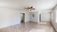 Located at 4001 S 16th St in Fort Smith, Arkansas, this single-story, 3-bedroom, 1-bathroom home offers a practical and well-organized layout. The open living room serves as the heart of the home, featuring light-toned luxury vinyl plank flooring, neutral gray walls, a textured ceiling, and a ceiling fan with integrated lighting. Natural light flows in through multiple windows, creating a bright and welcoming atmosphere. An arched pass-through detail adds a subtle architectural touch between the living and kitchen areas. The kitchen is efficiently designed with white cabinetry, dark countertops, a double-basin sink, a dishwasher, and a range, alongside a full-size refrigerator. Light LVP flooring continues throughout the kitchen, which opens conveniently toward the living space. Each of the three bedrooms is finished with plush carpeting and features a built-in closet with bi-fold doors, offering ample storage. The primary bedroom includes a spacious walk-in style closet with a full-length hanging rod. The single bathroom is clean and functional, equipped with a soaking tub and shower combo, wood-look tile flooring, white cabinetry, and a window for natural ventilation. A hallway connects the bedrooms and bathroom, completing this straightforward and comfortable floor plan.