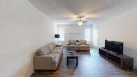 This single-floor residence offers a well-organized layout with multiple bedrooms, living areas, a dedicated dining space, and multiple bathrooms. The living room serves as a central gathering space, featuring durable wood-look flooring, a ceiling fan with light fixture, and natural light from multiple windows dressed with horizontal blinds. A fireplace with a simple white mantel adds a functional focal point to the room.

The galley-style kitchen is efficiently designed with gray cabinetry, light laminate countertops, and wood-look flooring that continues into the adjacent dining area. The layout provides ample cabinetry storage on both sides, along with a standard range and overhead microwave.

The bedrooms are carpeted and feature textured ceilings, ceiling fans, and windows that allow natural light to filter in. The primary bedroom benefits from sliding glass door access to an outdoor balcony or patio, offering outdoor views. Additional bedrooms are comparably sized and similarly finished.

The bathrooms include a full bath with a tiled tub-shower combination and a separate bath featuring a vanity with gray cabinetry, a large mirror, and a water closet. Neutral tones and consistent finishes are carried throughout the entire residence, creating a cohesive and functional living environment.