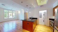 This well-appointed single-floor residence at 199 Lagrange Street in Newton, MA offers a thoughtfully designed open-concept layout with modern finishes throughout. Light hardwood flooring flows seamlessly across the living areas, reflecting an abundance of natural light that pours in through generously sized windows with views of lush greenery.

The kitchen serves as a central hub of the space, anchored by a striking island with rich warm-toned wood cabinetry and a bold black granite countertop, complemented by pendant lighting overhead. Stainless steel appliances — including a gas range, microwave, dishwasher, and a full-size refrigerator — complete the well-equipped culinary space. A dedicated in-unit laundry area with a stacked washer and dryer is conveniently accessible directly from the kitchen.

The living and bedroom areas are bright and open, benefiting from large windows and clean white walls with crisp crown molding. The primary bathroom is fully appointed with a dual-sink vanity, soaking tub, and a separate glass-enclosed shower, all finished in warm travertine-style tile. A separate half bath provides added convenience. The space combines clean contemporary design with functional comfort in a desirable Newton location.