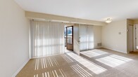 This thoughtfully designed 1-bedroom, 1-bathroom single-floor residence offers a functional and comfortable layout. The kitchen stands out with modern light wood cabinetry, granite-look countertops, stainless steel sink, and black Whirlpool appliances including an electric range and refrigerator, all illuminated by overhead flush lighting and easy-care tile flooring. The combined dining and living room is a bright, open space anchored by wall-to-wall carpeting and a large sliding glass door flanked by full-length vertical blinds, inviting abundant natural light and outdoor access. The bedroom is a comfortable retreat featuring soft carpet, a ceiling fan with light fixture, a natural light-admitting window with blinds, and an exceptionally wide built-in closet with full-panel bifold doors offering generous storage capacity. Additional closets throughout the unit provide further storage flexibility. The bathroom is clean and classic, finished with white subway tile wainscoting, a combined tub and shower, a white vanity with mirror, and warm vanity lighting. Overall, the unit presents a neutral, move-in-ready palette with practical finishes and a bright, airy ambiance throughout.