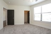 This single-floor residence offers a thoughtfully designed open-concept layout that seamlessly connects the living and kitchen areas. The kitchen is a standout feature, showcasing gray shaker-style cabinetry, granite-look countertops, a classic white subway tile backsplash, and stainless steel appliances including a refrigerator, gas range, and dishwasher. A large center island with pendant lighting provides additional prep space and a natural gathering point, while track lighting illuminates the entire cooking area. The open living room extends generously from the kitchen, finished with warm wood-look flooring, a ceiling fan, and access to a private balcony through a full-height glass door that brings in natural light. The bedrooms offer plush carpeting, ceiling fans, and large windows fitted with blinds for privacy and light control. Each bedroom benefits from a dedicated walk-in closet equipped with multi-tiered wire shelving systems, providing ample organized storage. The bathroom is well-appointed with a dark-framed vanity mirror, granite-topped cabinetry with drawers, and a full tub-and-shower combination finished with white tile surround and chrome fixtures. Clean neutral tones and consistent finishes throughout contribute to a cohesive, modern aesthetic.