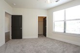 This single-floor residence offers a thoughtfully designed open-concept layout that seamlessly connects the living and kitchen areas. The kitchen is a standout feature, showcasing gray shaker-style cabinetry, granite-look countertops, a classic white subway tile backsplash, and stainless steel appliances including a refrigerator, gas range, and dishwasher. A large center island with pendant lighting provides additional prep space and a natural gathering point, while track lighting illuminates the entire cooking area. The open living room extends generously from the kitchen, finished with warm wood-look flooring, a ceiling fan, and access to a private balcony through a full-height glass door that brings in natural light. The bedrooms offer plush carpeting, ceiling fans, and large windows fitted with blinds for privacy and light control. Each bedroom benefits from a dedicated walk-in closet equipped with multi-tiered wire shelving systems, providing ample organized storage. The bathroom is well-appointed with a dark-framed vanity mirror, granite-topped cabinetry with drawers, and a full tub-and-shower combination finished with white tile surround and chrome fixtures. Clean neutral tones and consistent finishes throughout contribute to a cohesive, modern aesthetic.