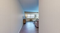 Located at 500 Fulton St E in the heart of Grand Rapids, Michigan, this 2-bedroom, 1-bathroom residence offers a practical and comfortable single-floor layout. The living room serves as the centerpiece of the home, featuring durable hardwood-style flooring, neutral-toned walls, and multiple windows that invite generous natural light. The open feel of the space is enhanced by clean lines and a straightforward design.

The galley-style kitchen is efficiently arranged with white cabinetry, dark countertops, a black refrigerator, and an electric range, complemented by open shelving that adds storage flexibility. A hallway connects the main living areas to the private quarters.

The spacious primary bedroom is notably generous in size, featuring plush carpeting, dual windows overlooking the outdoors, and ample room for a full furniture arrangement including a desk workspace. The second bedroom is equally well-appointed with carpet flooring, a closet with louvered doors, and a window for natural light.

The bathroom features classic light-blue subway tile wainscoting, a wall-mounted sink, a mirrored medicine cabinet, and a shower-tub combination. Throughout the residence, the consistent use of neutral tones and hardwood-style flooring in the main areas creates a cohesive, understated aesthetic well-suited for everyday living.