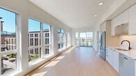 This well-appointed 2-bedroom, 2-bathroom residence offers a thoughtfully designed single-level layout that maximizes both comfort and functionality. The open-concept living and kitchen area is flooded with natural light through expansive floor-to-ceiling windows, which frame panoramic urban views of the surrounding cityscape. Light hardwood flooring flows seamlessly throughout the space, enhancing the clean, modern aesthetic defined by crisp white walls and recessed lighting.

The kitchen is outfitted with sleek white cabinetry, white quartz countertops, a matte black faucet, and a full suite of stainless steel appliances including a gas range, dishwasher, refrigerator, and built-in microwave. The open sightlines from the kitchen to the living area create a spacious, connected feel ideal for both everyday living and entertaining.

Both bedrooms are generously sized and feature large windows that bring in ample natural light and urban views. The primary bedroom offers a comfortable retreat with dedicated closet space equipped with adjustable shelving systems. The two bathrooms are finished in a clean, contemporary style with quality fixtures. A dedicated laundry room with a stacked washer and dryer adds everyday convenience, rounding out this efficient and modern urban residence.
