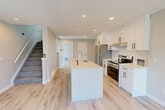Located at 9636 158 St NW in Edmonton, Alberta, this well-appointed two-storey home offers three bedrooms and three bathrooms across two thoughtfully designed floors. The main floor features an open-concept kitchen and living area bathed in natural light from multiple windows. The kitchen is finished with sleek white cabinetry, stainless steel appliances including a refrigerator and range, a central island with a quartz countertop and undermount sink, and recessed pot lighting throughout. Light hardwood-style flooring flows continuously across both levels, lending a clean and cohesive aesthetic to the entire home. The upper floor houses the generously sized primary bedroom, which features dual closets with wire shelving and direct access to a private ensuite bathroom. Additional bedrooms on the upper floor are well-proportioned, each benefiting from large windows that frame views of the surrounding neighbourhood and allow abundant natural light. The three bathrooms are finished with light cabinetry, quartz counters, and glass-enclosed showers. A dedicated hallway and two closets provide practical storage throughout. Neutral warm-grey wall tones and crisp white trim complete the modern, move-in-ready presentation of this Edmonton home.