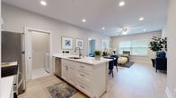 This single-floor residence showcases a thoughtfully designed open-concept layout that seamlessly connects the kitchen, dining, and living areas. The kitchen is anchored by a central island with a white quartz countertop and undermount sink, complemented by white shaker cabinetry, stainless steel appliances including a microwave, range, and refrigerator, and recessed lighting overhead. Light wood-style flooring extends throughout the main living areas, creating a cohesive and airy feel.

The living room offers generous natural light through large windows with blinds, and is finished with a ceiling fan and neutral wall tones that lend a calm, contemporary ambiance. Two well-proportioned bedrooms each feature ceiling fans, large windows with exterior views, and the same light flooring. The primary bedroom provides ample space for a full furniture arrangement.

Both bathrooms are appointed with white vanity cabinetry, quartz countertops, and large-format marble-look tile flooring, lending a clean and polished aesthetic. A dedicated in-unit laundry area with a full-size washer and dryer adds everyday convenience. The overall design emphasizes a bright, modern atmosphere with consistent finishes throughout.