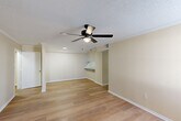 Located at 4445 Alvin Dark Ave in Baton Rouge, Louisiana, this single-story, 2-bedroom, 1-bathroom home offers a practical and comfortable layout. The open combined living and dining area is a central highlight, featuring warm wood-look flooring, neutral beige walls, a textured ceiling, and a ceiling fan with light fixture. A pass-through counter connects this space to the kitchen, enhancing the open feel. The galley-style kitchen is well-appointed with bold blue cabinetry, granite-look countertops, a double stainless steel sink, black appliances including a refrigerator, electric range, and dishwasher, plus ample upper and lower storage. Both bedrooms continue the wood-look flooring and neutral tones, each with natural light provided by windows with blinds. The primary bedroom is generously sized and features access to a walk-in closet outfitted with wire shelving and hanging rods for organized storage. The full bathroom includes a single-vanity, a tub/shower combo with tile surround, and a lighted mirror. Additional conveniences include a dedicated laundry area, hallway, and multiple closets throughout the home.