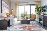 Located on Peachtree Street in Midtown Atlanta, this single-floor residence offers a thoughtfully designed layout with modern finishes throughout. The open living area features dark hardwood flooring, soaring angled ceilings, and a ceiling fan, with floor-to-ceiling sliding glass doors that flood the space with natural light and provide access to a private balcony overlooking lush tree canopy views. The kitchen is outfitted with stainless steel appliances, quartz countertops, a subtle blue tile backsplash, and a combination of white upper cabinetry and light wood lower cabinets, creating a clean, contemporary aesthetic. The bedrooms are carpeted and bright, each benefiting from large windows that frame verdant outdoor views. The primary bathroom features a dual-sink vanity with wood-toned cabinetry, quartz countertops, a wide frameless mirror, and modern lighting fixtures. The secondary bathroom offers a full tub-shower combination with white tile surround and a matching single-sink vanity. Clean white walls, consistent modern hardware, and an abundance of natural light tie the residence together, creating a cohesive and comfortable living environment in one of Atlanta's most vibrant neighborhoods.