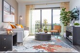 Located on Peachtree Street in Midtown Atlanta, this single-floor residence offers a thoughtfully designed layout with modern finishes throughout. The open living area features dark hardwood flooring, soaring angled ceilings, and a ceiling fan, with floor-to-ceiling sliding glass doors that flood the space with natural light and provide access to a private balcony overlooking lush tree canopy views. The kitchen is outfitted with stainless steel appliances, quartz countertops, a subtle blue tile backsplash, and a combination of white upper cabinetry and light wood lower cabinets, creating a clean, contemporary aesthetic. The bedrooms are carpeted and bright, each benefiting from large windows that frame verdant outdoor views. The primary bathroom features a dual-sink vanity with wood-toned cabinetry, quartz countertops, a wide frameless mirror, and modern lighting fixtures. The secondary bathroom offers a full tub-shower combination with white tile surround and a matching single-sink vanity. Clean white walls, consistent modern hardware, and an abundance of natural light tie the residence together, creating a cohesive and comfortable living environment in one of Atlanta's most vibrant neighborhoods.