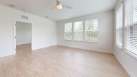 This well-appointed 1,050 sq ft single-floor residence in North Augusta, SC features 2 bedrooms, 2 bathrooms, and 2 closets designed with a clean, modern aesthetic. Light-toned luxury vinyl plank flooring flows throughout, complementing the crisp white walls and abundant natural light. The open-concept kitchen and living area serves as the heart of the home, showcasing white shaker cabinetry with matte black hardware, a white quartz island with pendant lighting, a subway tile backsplash, and a full suite of stainless steel appliances. The spacious living room features large windows with views of surrounding greenery and a ceiling fan overhead. The 170 sq ft primary bedroom offers multiple windows, generous natural light, and direct access to a private en-suite bathroom featuring a double vanity with framed mirrors, quartz countertops, and a glass-enclosed walk-in shower with large-format tile and accessibility grab bars. The second bedroom is equally bright, with windows overlooking the community exterior. Both bedrooms include dedicated closets. The unit's neutral palette, modern fixtures, and light-filled rooms create a clean, inviting atmosphere throughout.