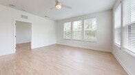 This well-appointed 1,050 sq ft single-floor residence in North Augusta, SC features 2 bedrooms, 2 bathrooms, and 2 closets designed with a clean, modern aesthetic. Light-toned luxury vinyl plank flooring flows throughout, complementing the crisp white walls and abundant natural light. The open-concept kitchen and living area serves as the heart of the home, showcasing white shaker cabinetry with matte black hardware, a white quartz island with pendant lighting, a subway tile backsplash, and a full suite of stainless steel appliances. The spacious living room features large windows with views of surrounding greenery and a ceiling fan overhead. The 170 sq ft primary bedroom offers multiple windows, generous natural light, and direct access to a private en-suite bathroom featuring a double vanity with framed mirrors, quartz countertops, and a glass-enclosed walk-in shower with large-format tile and accessibility grab bars. The second bedroom is equally bright, with windows overlooking the community exterior. Both bedrooms include dedicated closets. The unit's neutral palette, modern fixtures, and light-filled rooms create a clean, inviting atmosphere throughout.