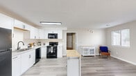 Located at 1408 Brookside Dr in Raleigh, NC, this one-bedroom, one-bathroom single-floor home offers a well-designed layout with modern finishes throughout. The open-concept kitchen and living area serves as the heart of the home, featuring light gray wood-look flooring that flows seamlessly across the space. The kitchen is outfitted with crisp white shaker-style cabinetry, black appliances including a range, microwave, dishwasher, and refrigerator, along with a sink and ample counter space. A central island adds additional prep and storage functionality. The adjoining living area is bright and welcoming, with large sliding glass doors that flood the room with natural light and provide views of the surrounding greenery. A secondary window enhances the airy feel of the space. The bedroom is comfortably sized, featuring plush carpeting, a window with outdoor views, and a closet for storage. Neutral wall tones throughout the home create a clean, cohesive aesthetic. The bathroom is finished with a white vanity, wood-look flooring, and a shower-tub combination. A dedicated closet rounds out the functional layout of this well-appointed Raleigh home.