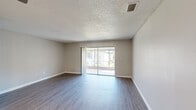 Located in Kissimmee, FL, this single-floor, 3-bedroom, 2-bathroom home offers a practical and comfortable layout designed for everyday living. The entrance leads into hallways finished with durable wood-look flooring that flows consistently throughout the home, creating a cohesive and clean aesthetic. The combined living and dining area is generously sized, featuring a textured ceiling, neutral-toned walls, and a sliding glass door that fills the space with natural light and opens directly onto a private balcony. The kitchen is efficiently designed with granite countertops, light cabinetry, and includes a full appliance suite — electric range, over-the-range microwave — alongside a window for natural ventilation. A dedicated pantry and utility room add practical storage solutions. The spacious primary bedroom features its own ceiling fan and ample closet space, while the two additional bedrooms are well-proportioned, each equipped with ceiling fans and built-in closets. Both bathrooms are finished in crisp white with tub-shower combinations, vanity cabinetry, and wood-look flooring. With seven closets spread throughout, storage is abundant. The home's neutral palette and consistent finishes lend a clean, move-in ready feel throughout.