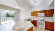 Located at 4341 Cortina Cir in Fort Myers, Florida, this three-story, three-bedroom, three-bathroom home offers a well-organized layout spread across three distinct levels. The ground floor houses an attached garage with automatic opener, a water heater, and utility access, providing practical storage and parking. The main living level features a bright, open-concept space that seamlessly connects the living room, dining area, and kitchen. Light tile flooring, a tray ceiling with a ceiling fan, and a sliding glass door leading to an outdoor balcony give this floor an airy, welcoming feel. The kitchen stands out with rich wood cabinetry, a classic subway tile backsplash, a sweeping marble-look countertop with a breakfast bar, and white appliances. The upper floor is home to the bedrooms, including a well-proportioned primary bedroom featuring vaulted ceilings, plush carpet, and a striking arched window that floods the room with natural light and outdoor views. The bathrooms are finished with wood-tone vanities, marble-look countertops, tile flooring, and glass-enclosed walk-in showers. A dedicated laundry room with a full-size washer and dryer adds everyday convenience. Multiple closets and a hallway complete the upper level, making this home both functional and comfortable.