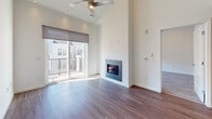 Located at 119 Searing Avenue in Mineola, NY, this contemporary two-floor residence showcases clean, modern design and high-quality finishes throughout. The kitchen is a standout feature, outfitted with crisp white cabinetry extending to the ceiling, neutral quartz-style countertops, a white subway tile backsplash, and a full suite of stainless steel appliances including a gas range, built-in microwave, dishwasher, and French door refrigerator. A professional-style spring-neck faucet adds a refined touch to the undermount sink. The living area is particularly impressive, boasting soaring double-height ceilings, rich hardwood-style flooring, and a wall-mounted fireplace that serves as a focal point. A ceiling fan and large sliding glass doors lead to a private balcony, flooding the space with natural light and offering outdoor views. Bedrooms are carpeted for comfort, with ample natural light filtering through roller shade-equipped windows. The bathroom is finished with a sleek vanity featuring a quartz countertop, an undermount sink, and a full tub-shower combination enclosed by a frameless sliding glass door, complemented by matching hardwood-style flooring. Throughout the residence, a neutral color palette and modern detailing create a cohesive, contemporary ambiance.