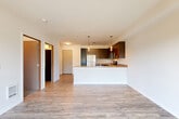 Located at 5703 244th St SW in Shoreline, Washington, this one-bedroom, one-bathroom unit offers a well-designed open-concept layout across a single floor. Light-toned hardwood-style flooring flows throughout the main living areas, creating a cohesive and contemporary aesthetic.

The kitchen is a standout feature, outfitted with dark espresso cabinetry, a full suite of stainless steel appliances including a refrigerator, range, microwave, and dishwasher, and a peninsula with a light-toned countertop that doubles as a breakfast bar. Pendant lighting above the peninsula adds a modern touch. The kitchen opens seamlessly into the combined dining and living area, which is brightened by a large sliding glass door leading to a private balcony with open views of the surrounding Shoreline neighborhood and mature trees.

The bedroom features plush carpeting and access to a generously sized walk-in closet with wrap-around hanging rods. The full bathroom includes a tub-shower combination, a dark-cabinet vanity with a white sink, and wood-style flooring. A dedicated in-unit laundry area adds everyday convenience. The unit's clean, neutral palette and modern finishes throughout make it a well-appointed and functional living space.
