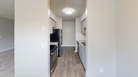 Located at 1751 Dogwood Rd in Charleston, South Carolina, this single-floor, 2-bedroom, 2-bathroom home offers a well-organized layout designed for comfortable everyday living. The galley-style kitchen is a standout feature, boasting granite countertops, gray shaker-style cabinetry, a subway tile backsplash, and stainless steel appliances including a range, microwave, and refrigerator. Wood-look flooring runs through the kitchen, which opens into a bright dining area accented by a stylish chandelier and a window overlooking the outdoors. Both bedrooms are carpeted and finished with neutral tones, offering a cozy and restful atmosphere. The primary bedroom includes a ceiling fan and natural light from a window, while the second bedroom is similarly appointed. Each bathroom features a granite-topped vanity with a undermount sink, brushed nickel fixtures, and a full tub-shower combination. Textured ceilings throughout lend a consistent finish to the space. Connecting hallways provide practical flow between rooms. The overall aesthetic is clean and modern, with cohesive neutral tones, updated fixtures, and quality finishes that make this a move-in-ready home in the Charleston area.