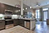 Located at 2245 Interstate North Pkwy SE in Atlanta, Georgia, this single-floor residence offers a thoughtfully designed interior with contemporary finishes throughout. The kitchen serves as a functional centerpiece, showcasing dark espresso cabinetry, stainless steel appliances including a French door refrigerator, microwave, and range, complemented by granite countertops, a white subway tile backsplash, and pendant lighting. A kitchen island with bar seating provides a practical and stylish space for dining or entertaining, while wood-look flooring ties the area together seamlessly.

The living area exudes a warm, sophisticated ambiance with neutral toned walls, wood-look flooring, and generous windows dressed with layered curtains that invite natural light. A pair of large-scale abstract artworks anchors the space above a plush sectional sofa, while an open shelving unit adds a curated, gallery-like quality.

The bedrooms are carpeted and serene, each benefiting from large windows with views of lush greenery. Thoughtful details such as decorative wall art, ample storage, and soft neutral palettes create restful retreats.

The bathroom is finished with wood-look tile flooring, a dark vanity with granite countertops, and a full soaking tub with a classic subway tile surround, delivering a clean and polished aesthetic throughout.