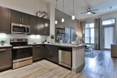 Located at 2245 Interstate North Pkwy SE in Atlanta, Georgia, this single-floor residence offers a thoughtfully designed interior with contemporary finishes throughout. The kitchen serves as a functional centerpiece, showcasing dark espresso cabinetry, stainless steel appliances including a French door refrigerator, microwave, and range, complemented by granite countertops, a white subway tile backsplash, and pendant lighting. A kitchen island with bar seating provides a practical and stylish space for dining or entertaining, while wood-look flooring ties the area together seamlessly.

The living area exudes a warm, sophisticated ambiance with neutral toned walls, wood-look flooring, and generous windows dressed with layered curtains that invite natural light. A pair of large-scale abstract artworks anchors the space above a plush sectional sofa, while an open shelving unit adds a curated, gallery-like quality.

The bedrooms are carpeted and serene, each benefiting from large windows with views of lush greenery. Thoughtful details such as decorative wall art, ample storage, and soft neutral palettes create restful retreats.

The bathroom is finished with wood-look tile flooring, a dark vanity with granite countertops, and a full soaking tub with a classic subway tile surround, delivering a clean and polished aesthetic throughout.