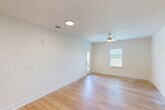 This single-story home in Valdosta, Georgia offers a clean, modern aesthetic throughout its three bedrooms, two bathrooms, dedicated laundry area, and open-concept kitchen and living room. Light-toned hardwood flooring runs consistently across the living spaces, creating a warm, cohesive look that complements the crisp white walls and bright interiors.

The kitchen is a standout feature, showcasing white shaker-style cabinetry with matte black hardware, white quartz countertops, a subway tile backsplash, and a central island with an undermount sink. Stainless steel appliances, including a French door refrigerator, range, and over-the-range microwave, complete the contemporary setup.

The spacious primary bedroom provides a generous and comfortable retreat. All bedrooms feature light wood flooring, ceiling fans with integrated lighting, and windows fitted with blinds that allow for natural light and privacy. An exterior door in one room leads to an outdoor area, adding convenience and additional access.

Both bathrooms are finished with white tiled tub-and-shower combinations and matte black fixtures and grab bars, offering a consistent and practical design. The laundry area includes wire shelving and the necessary utility hookups.

Overall, this home presents a fresh, move-in-ready environment with consistent modern finishes throughout.