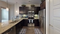 Located on Manderville Lane in Dallas, Texas, this single-story residence offers a thoughtfully designed interior with a cohesive blend of modern finishes and functional layout. The kitchen serves as a central highlight, featuring rich dark cabinetry extending to the ceiling, a subway tile backsplash, granite countertops, stainless steel appliances, and a peninsula with pendant lighting overhead — ideal for both cooking and casual dining. Dark hardwood-style flooring flows throughout the main living areas, anchoring the open, airy feel of the space.

The living area is generously proportioned, bathed in natural light, and equipped with a ceiling fan and track lighting, lending versatility to the space. Neutral wall tones throughout create a calm, welcoming atmosphere. Bedrooms are finished with plush carpet, ceiling fans, and large windows fitted with blinds that allow ample natural light while maintaining privacy.

The bathroom is well-appointed with dark cabinetry, granite countertops, an undermount sink, a glass-enclosed shower, and direct access to a spacious walk-in closet outfitted with multi-level shelving and hanging rods. The overall design reflects a clean, contemporary aesthetic suited to comfortable everyday living.