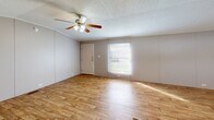 Located at 600 Holly Drive in Albany, Georgia, this single-story home offers three bedrooms and three full bathrooms within a efficient, well-organized floor plan. The exterior features brown vertical lap siding with white skirting, set on a green lawn with entry stairs leading to the front door.

Inside, wood-look plank flooring runs throughout the home, creating a warm and cohesive aesthetic. The open-concept kitchen is a standout feature, boasting white cabinetry, dark countertops, a stone-tile backsplash, and black appliances including a range, microwave, and refrigerator. A window over the sink brings in natural light, and vaulted ceiling lines add a sense of openness to the space.

The bedrooms are comfortably sized with neutral wall paneling and ceiling fans or flush-mount light fixtures. The primary bedroom includes a dedicated closet with a clothing rod. Additional bedrooms offer similar layouts with arched interior doors providing access to hallways and closets.

Each of the three bathrooms includes a tub/shower combo with white surrounds, standard fixtures, and stone-look vanity countertops. Two hallways connect the living areas to the bedrooms efficiently. A dedicated closet offers additional storage. The fenced backyard provides a private outdoor space, completing this functional and move-in-ready home.