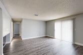 Located at 597 Fairplay Way in Aurora, Colorado, this 2-bedroom, 1-bathroom single-story home offers a clean, modern interior with a cohesive neutral color palette throughout. The open-concept layout connects the kitchen and living room, creating a functional and efficient living space. The living room is generously sized, featuring wood-look laminate flooring, soft gray walls, a textured ceiling, and a sliding glass door with vertical blinds that fills the room with natural light. The kitchen is well-appointed with rich dark-espresso cabinetry, light countertops, a tile backsplash, stainless steel appliances including a range and refrigerator, and a built-in sink — all set on matching wood-look flooring. Both bedrooms are comfortably sized, with the primary bedroom offering ample room, and both feature the same consistent gray tones, wood-look flooring, and textured ceilings. Two closets provide practical storage solutions. The bathroom includes a full tub-shower combination, a dark-cabinet vanity with a white countertop, and coordinating flooring. Clean white trim and baseboards run throughout, giving the home a polished, move-in-ready feel.