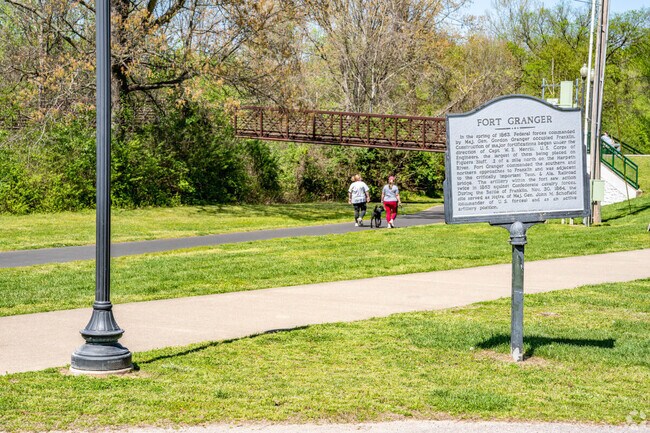 Two people walk a dog through Fort Granger Park.