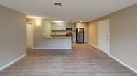 This single-floor unit offers a well-designed, functional layout that balances comfort and practicality throughout. The open-concept living and kitchen area serves as the heart of the space, with light hardwood-style flooring, neutral taupe walls, and a textured ceiling that carries through the common areas. A sliding glass door floods the living room with natural light and provides direct access to a private outdoor patio.

The kitchen is thoughtfully appointed with gray shaker-style cabinetry, granite-look countertops, and a full suite of stainless steel appliances, including a refrigerator, range with oven, and over-the-range microwave. A peninsula counter with matching granite surfaces connects the kitchen to the living area, creating a seamless flow ideal for everyday living and entertaining.

The two bedrooms feature plush wall-to-wall carpeting and neutral-toned walls, offering a calm and restful atmosphere. Each room benefits from natural light via double-pane windows. One bedroom includes a built-in closet with sliding doors and dedicated hanging and shelving space, providing ample storage.

The bathroom is finished with light tile flooring, a granite-topped vanity with gray cabinetry, and a full tub-shower combination. The cohesive design palette of warm neutrals and modern finishes gives the entire unit a clean, updated feel.