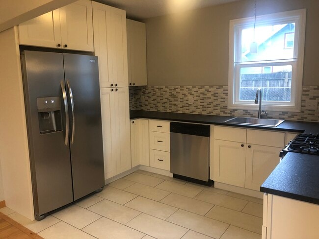 pen concept kitchen. Stainless steel appliances, large sink with pull-out faucet, dishwasher, granite counters, and tiled backsplash. All new cabinetry with plenty of storage, including large pantry. - 4842 NE Mallory Ave