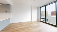 This sleek, urban apartment offers 780 square feet of thoughtfully designed living space in the heart of Wilmington, Delaware. Located at 801 Orange St, the unit showcases a contemporary open floor plan that maximizes functionality and natural light. The spacious primary bedroom, measuring 200 square feet, provides ample room for rest and relaxation.

The kitchen is a standout feature, boasting modern gray cabinetry, stainless steel appliances, and a pristine white countertop with a built-in sink. The L-shaped design efficiently utilizes space, opening seamlessly into the living area. Light wood flooring flows throughout, creating a warm and cohesive aesthetic.

Floor-to-ceiling windows in the living room and bedroom offer breathtaking city views, flooding the space with natural light and creating an airy ambiance. The bathroom exudes luxury with its marble-inspired tiled walls, glass-enclosed shower, and contemporary fixtures.

The apartment's clean lines, neutral color palette, and minimalist design contribute to its modern appeal. Recessed lighting and a statement light fixture in the kitchen add to the sophisticated atmosphere. With its prime location and high-end finishes, this apartment represents the epitome of urban living in Wilmington.